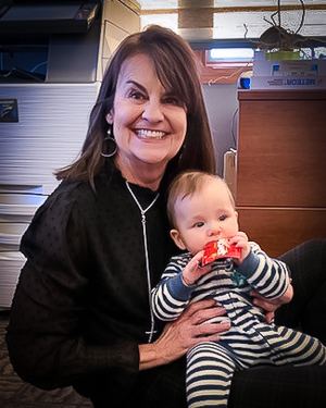 Georgia Weis holds a baby while sitting on the floor of her office