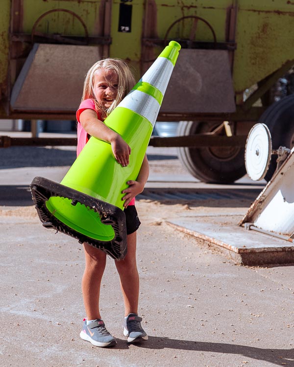 child carrying safety cone on farm