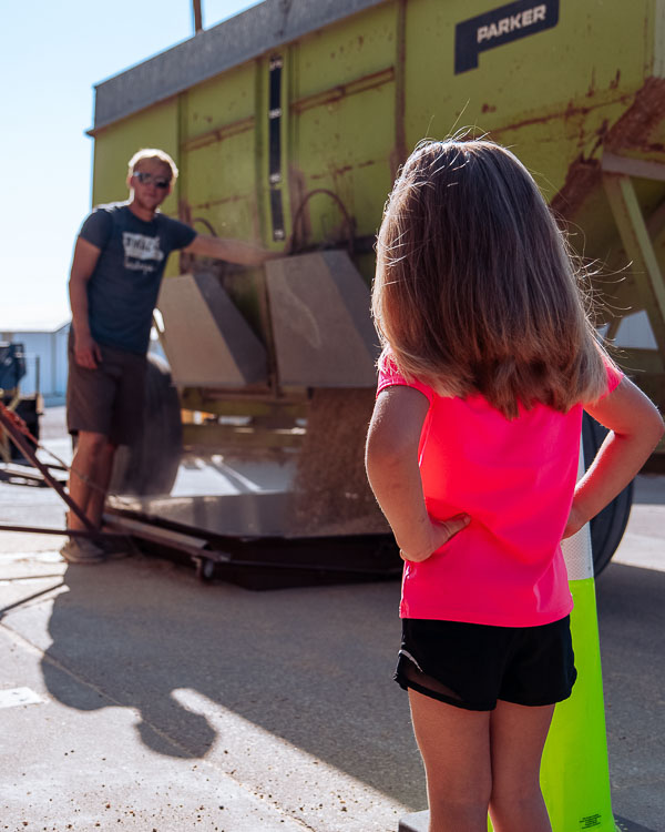 child watches farmer unload grain