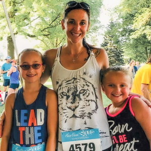 Beth posing with two of her children while wearing a running bib.